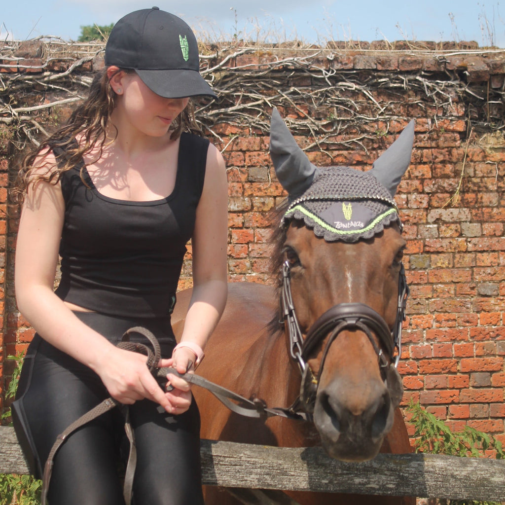 Woman wearing a black crop top with a silver green equestrian logo