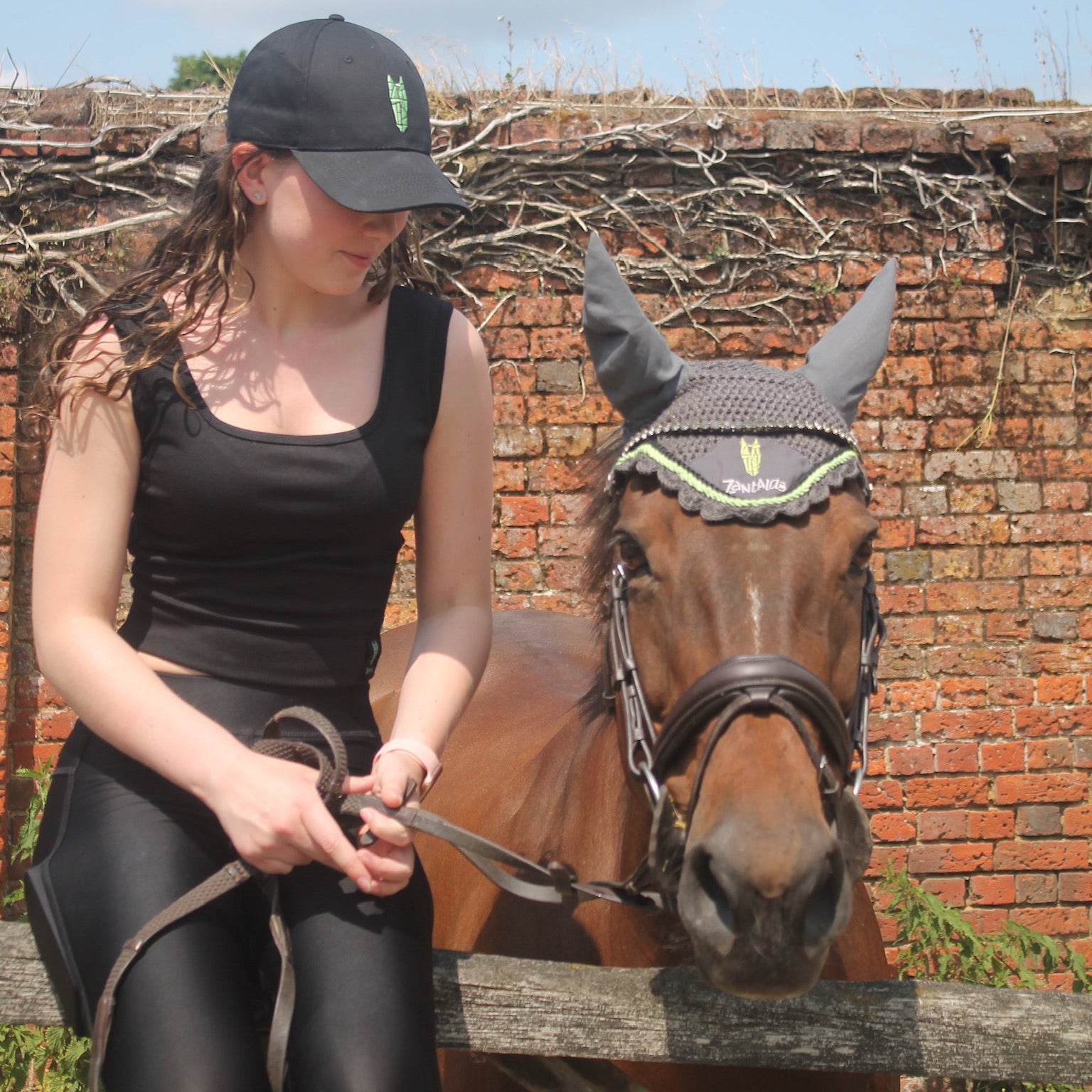 Woman wearing a black crop top with a silver green equestrian logo