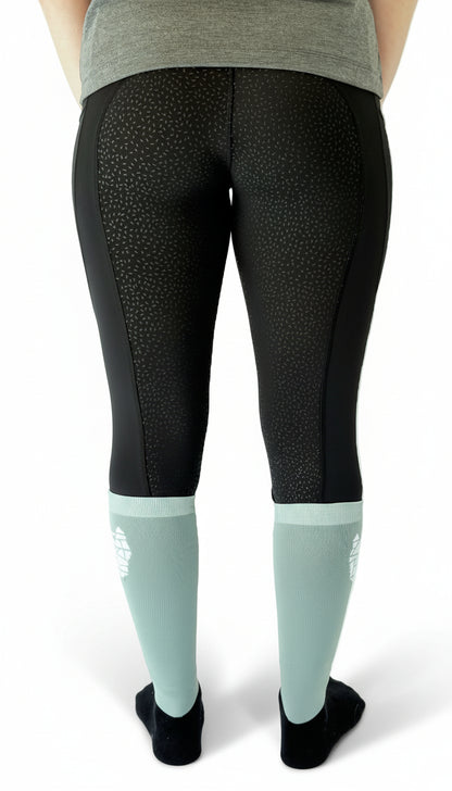 Rear view of a woman wearing black equestrian riding leggings with a full gel seat and double pockets