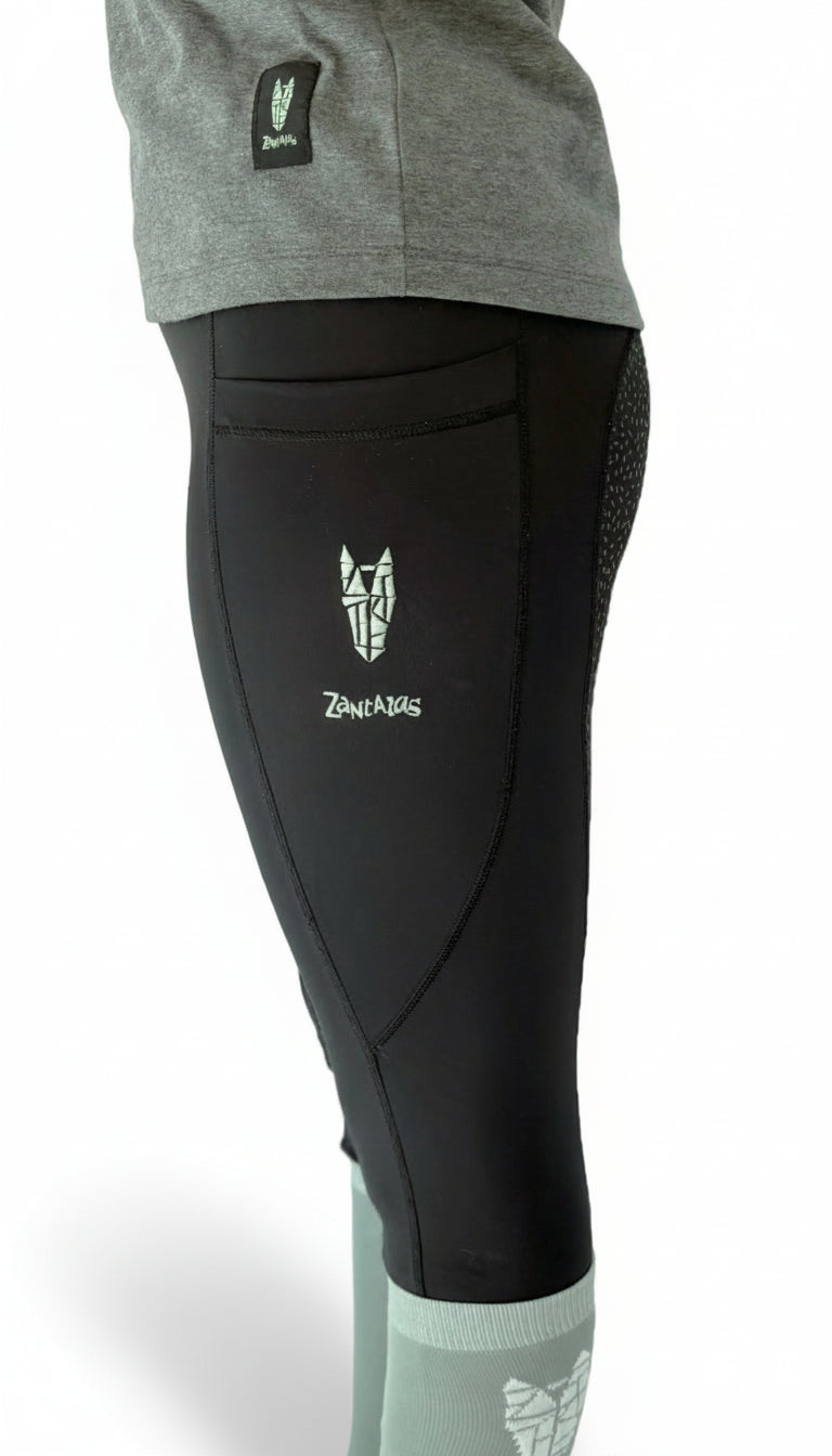 Side view of a woman wearing equestrian riding leggings with a full gel seat, double pockets and a striking horse head logo on the side pocket