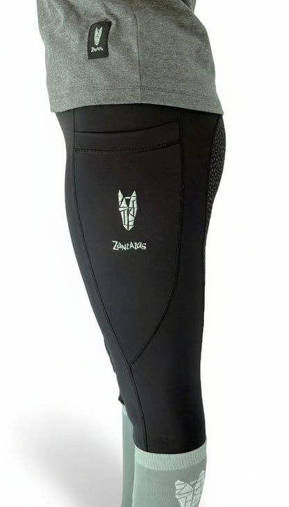 Side view of a woman wearing equestrian riding leggings with a full gel seat, double pockets and a striking horse head logo on the side pocket
