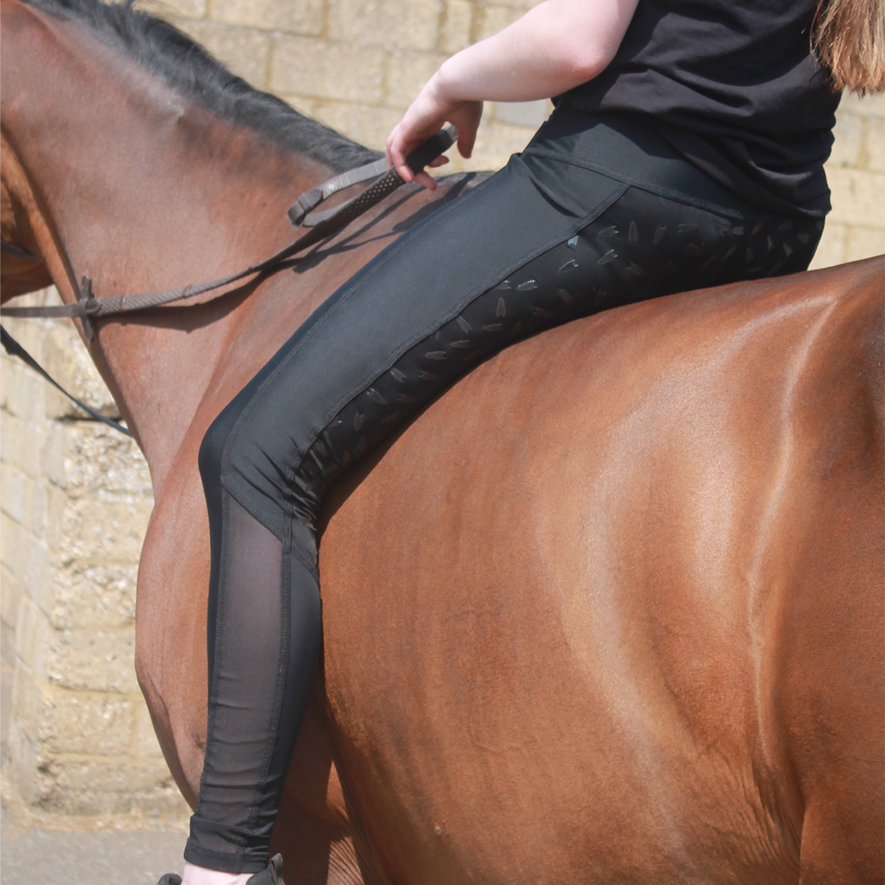 Person riding a horse wearing black leggings with a cooling mesh panel along the lower leg