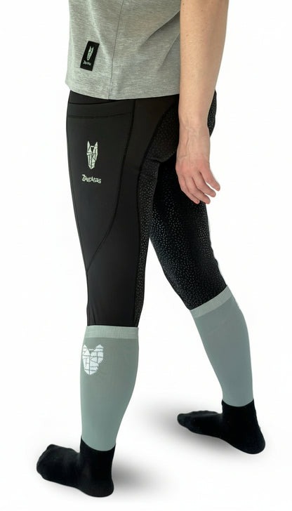 A woman wearing equestrian riding leggings with a full gel seat and striking horse head logo