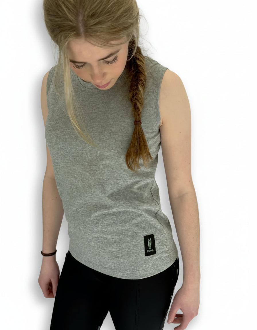 Teenage girl wears a sleeveless grey tshirt with a striking silver green horse head logo and black riding leggings