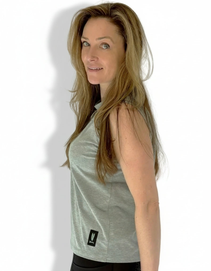 Woman wears a sleeveless grey tshirt with striking equestrian logo and black riding leggings