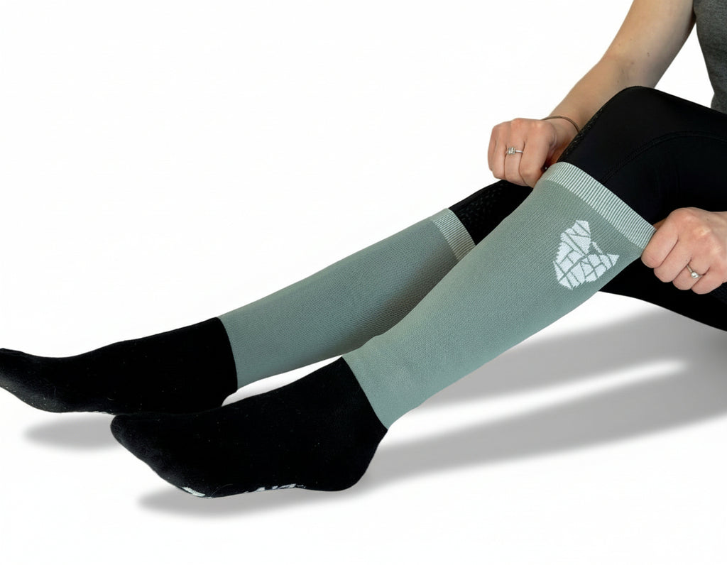 A woman wearing black and gray/green equestrian riding socks with a warm reinforced foot