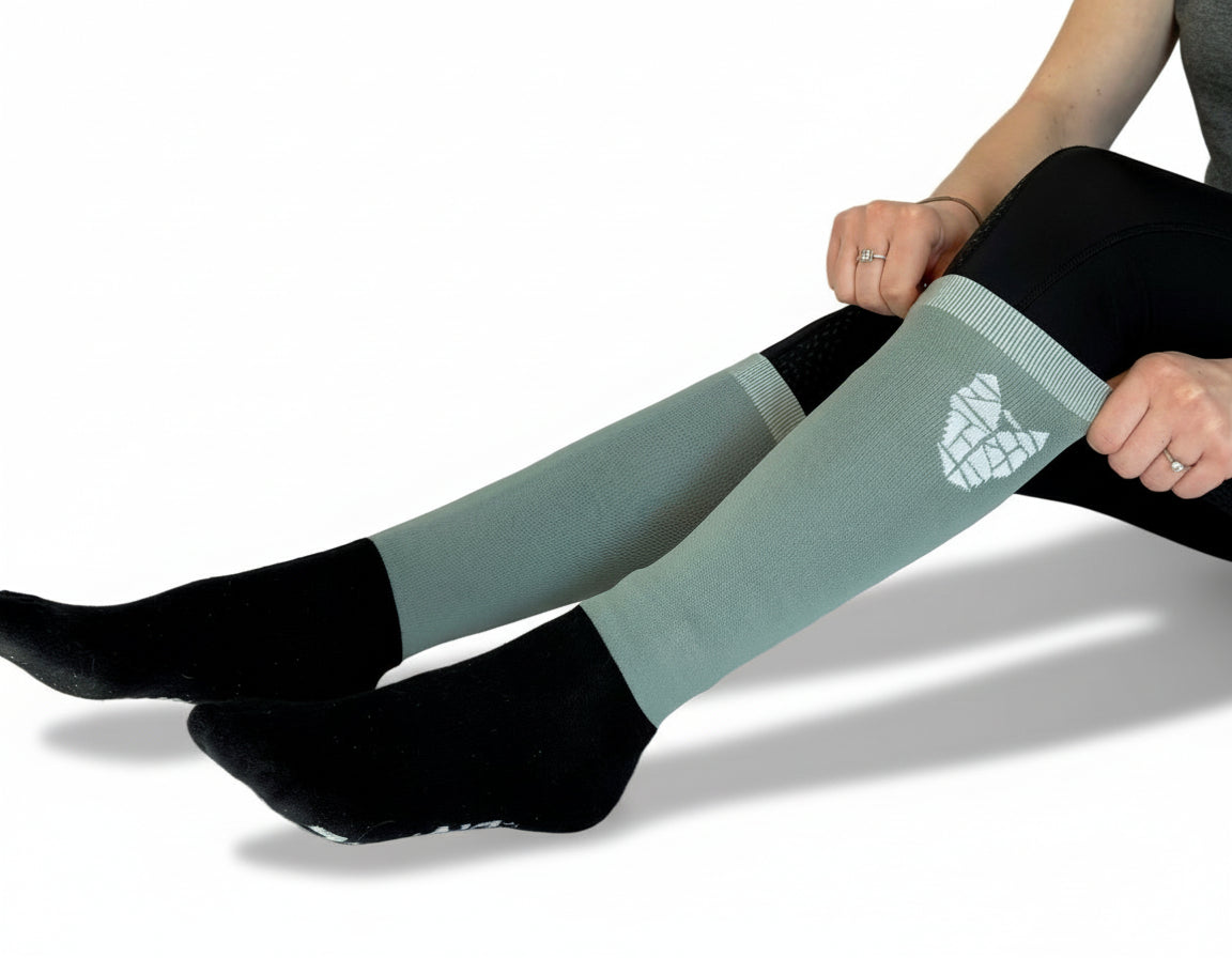 A woman wearing black and gray/green equestrian riding socks with a warm reinforced foot