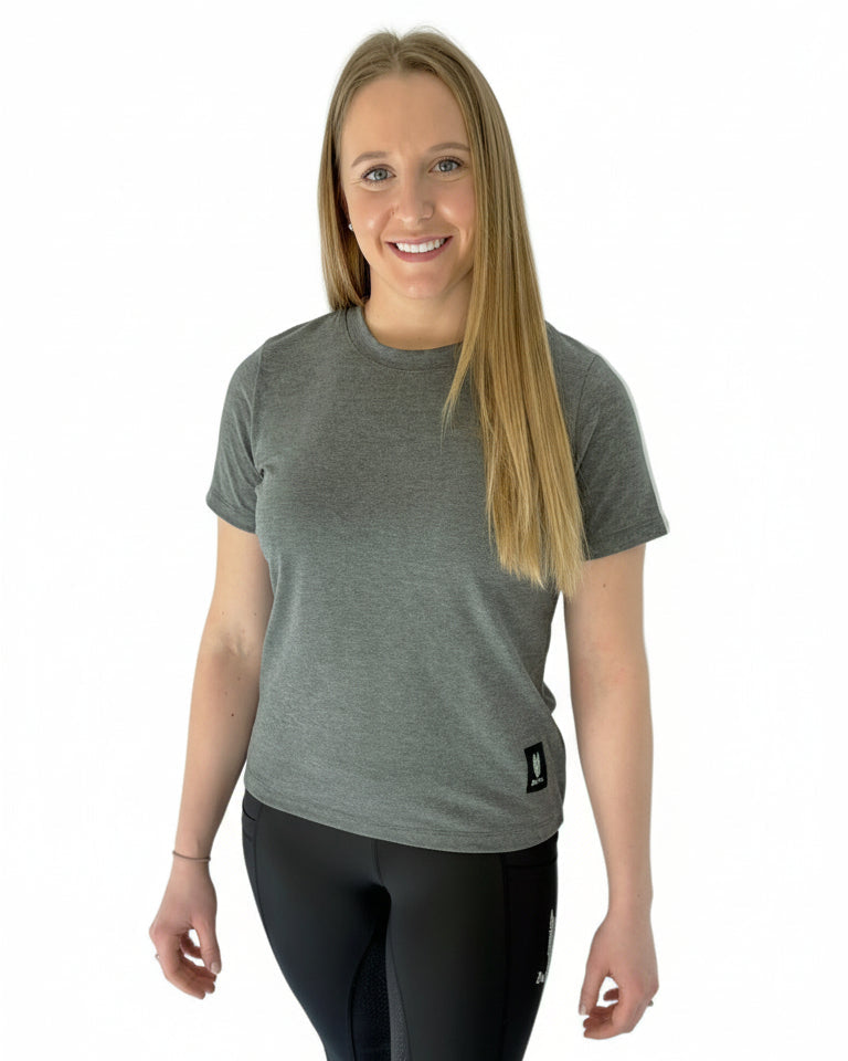 Woman wearing an equestrian outfit including a grey t-shirt with a silver green logo